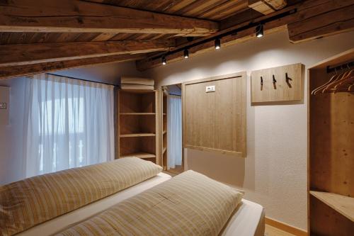 a bedroom with a bed and a window and shelves at Appartamento Sas Ciapel con biosaun in Arabba