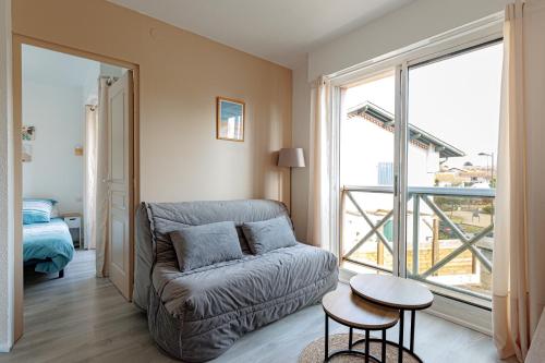 a living room with a couch and a large window at Appartement Les Jardins in Saint-Vincent-de-Tyrosse