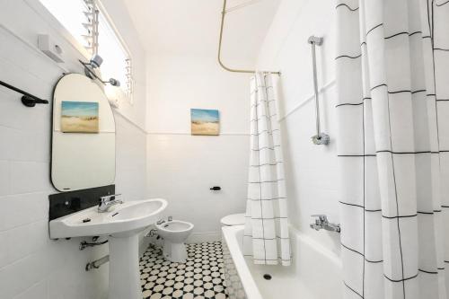 a white bathroom with a sink and a toilet at La Casa de la Punta in San Pol de Mar