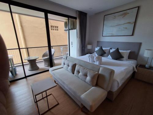 a bedroom with a large white bed and a couch at Rawai Sea Escape 1BR With Rooftop Pool in Rawai Beach