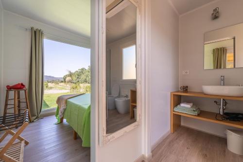 a bathroom with a mirror and a bed and a sink at Macondo Agriliving Tiny Houses in Castiadas
