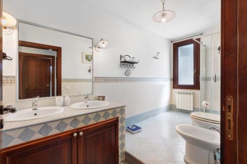 a bathroom with two sinks and a toilet and a mirror at Villa Dalia con piscina in Partinico