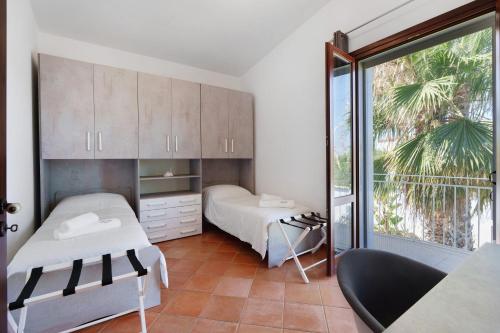 a bedroom with two beds and a large window at Villa Dalia con piscina in Partinico