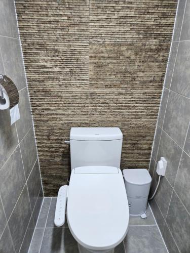 a bathroom with a white toilet and a tile wall at Tohyang Traditional House in Bonghwa