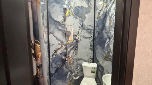 a bathroom with a marble wall with a toilet at Over City Hostel in Margilan