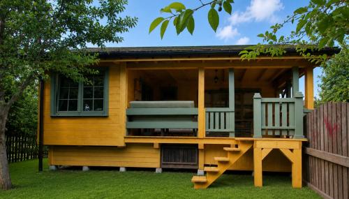 a tiny house with a deck and two chairs at Osada Bura Polana - drewniane domki z sauną in Ujsoły