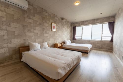 a hotel room with two beds and a window at Beppu Ohana in Beppu