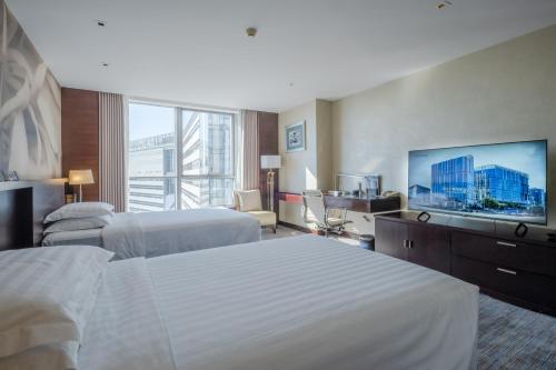 a hotel room with two beds and a flat screen tv at China National Convention Center Grand Hotel in Beijing