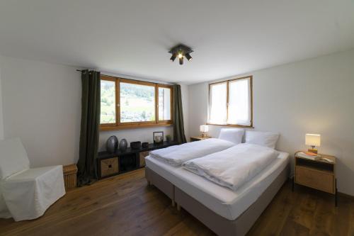 a bedroom with a large white bed and two windows at Chalet Bergblick in Wildhaus
