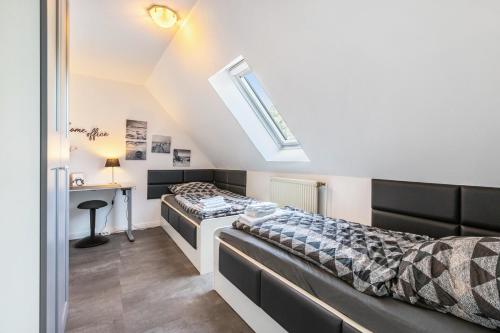 two beds in a room with a desk and a window at Fewo Kleine Auszeit 100qm in Friedrichskoog
