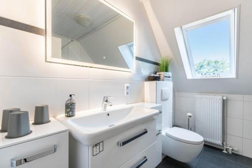 a white bathroom with a sink and a toilet at Fewo Kleine Auszeit 100qm in Friedrichskoog