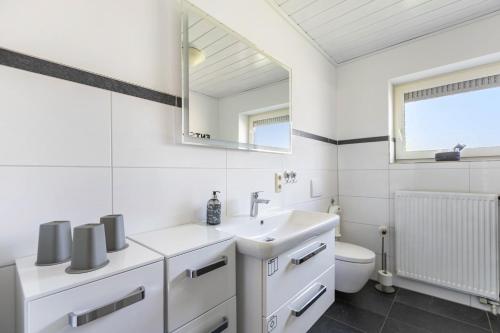 a white bathroom with a sink and a toilet at Fewo Freiraum mit großer Terrasse in Friedrichskoog