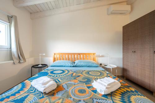 a bedroom with a large bed with two towels on it at Macondo Agriliving Apartments in Castiadas