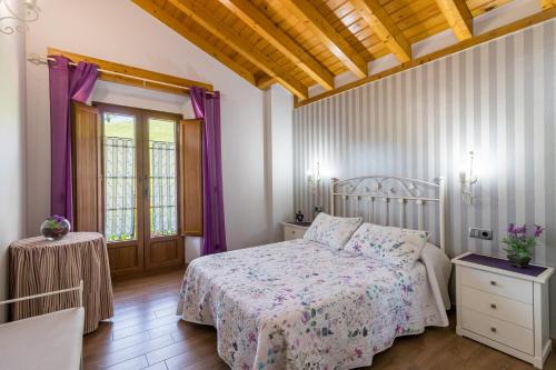 a bedroom with a bed and purple curtains at La Cabaña de Manuela in Bustantegua
