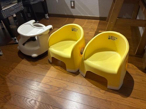 two yellow chairs and a toilet on a wooden floor at mintstay kochi in Kochi