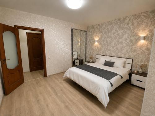 a bedroom with a large white bed and a wooden floor at Atlant luxury Big Family Perlina Apart on Golovna поряд з ТЦ Депот in Chernivtsi
