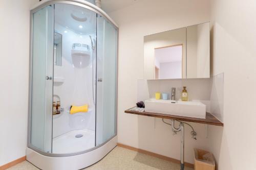 a bathroom with a glass shower and a sink at Beppu Ohana in Beppu