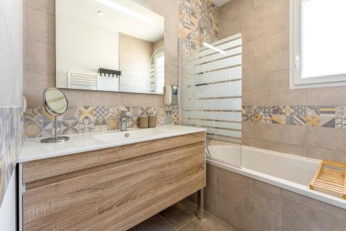 a bathroom with a sink and a tub and a mirror at Villa Hestia in Goudargues