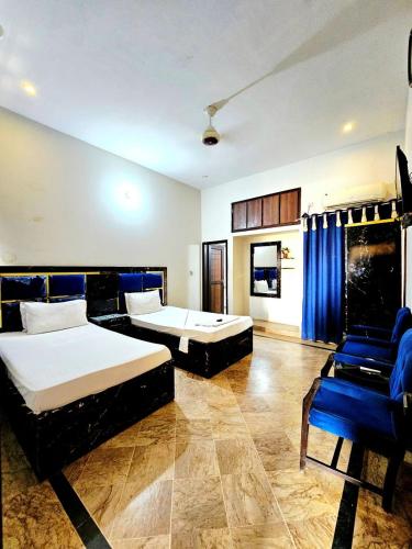 a bedroom with two beds and a blue chair at Royal Villa in Karachi