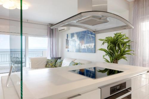 a white kitchen with a large mirror above a sink at Ciel Collection - Luxury Seafront Living in Perea