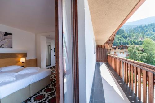 a bedroom with a balcony with a bed and a view at Royal Olympic Hotel in Pinzolo