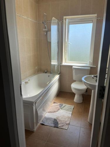 a bathroom with a tub and a toilet and a window at Sruthan na Teorainn in Carraroe