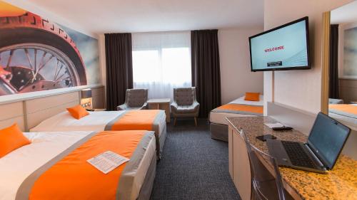 a hotel room with two beds and a laptop on a desk at Hotel Le Paddock in Magny-Cours