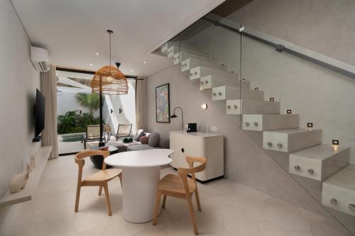 a living room with a table and chairs and a staircase at The Arc House Canggu in Canggu