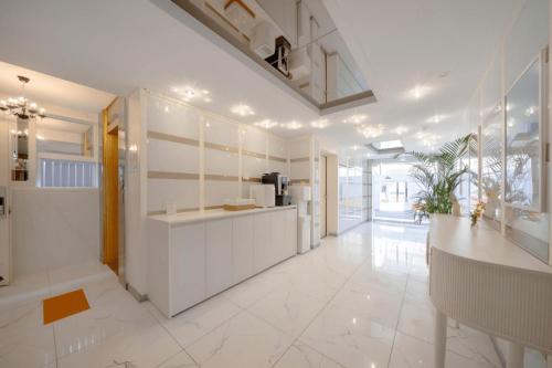 a kitchen with white walls and a large white tile floor at Gimhae Tour Hotel in Gimhae