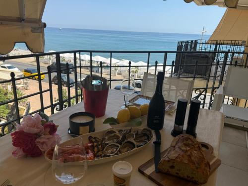 a table with a plate of food and a view of the beach at Victoria Beach Front de Mer Luxury Apartment in Menton