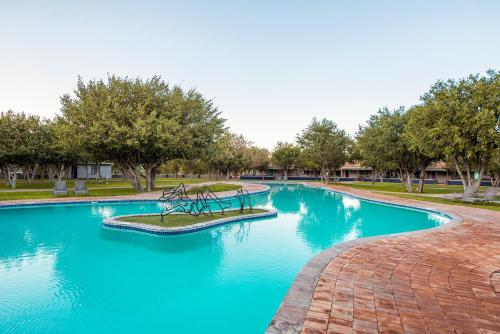 a swimming pool with blue water in a park at Gondwana Damara Mopane Lodge in Mopane Pos