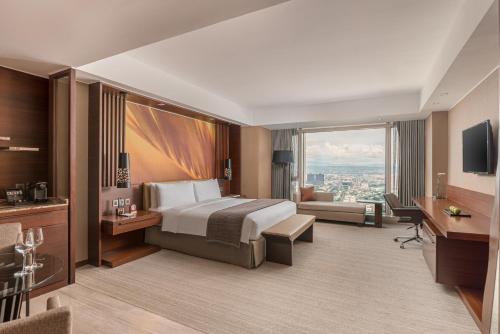 a hotel room with a bed and a large window at Marco Polo Ortigas Manila in Manila