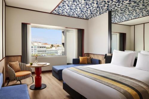 a hotel room with a bed and a table and a window at Avani Avenida Liberdade Lisbon Hotel in Lisbon