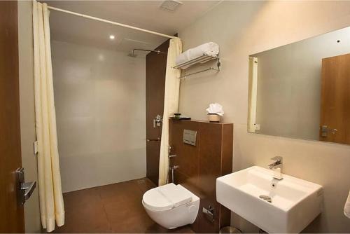 a bathroom with a sink and a toilet and a mirror at Hotel Keerthi in Trivandrum