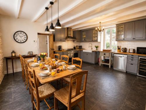 a kitchen with a long wooden table and chairs at La spacieuse maison des miots in Saint-Simeux