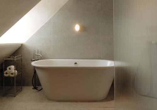 a white bath tub in a bathroom with a roof at Ausma Hotel in Kuldīga