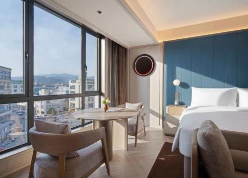 a bedroom with a bed and a table and a large window at Orange Crystal Hotel Ningbo Ninghai in Ninghai