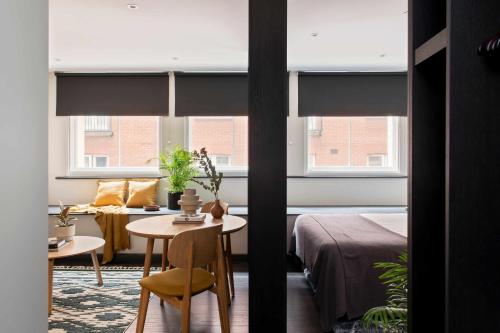 a room with a bed and a table and two windows at COVE Cannon Street in London