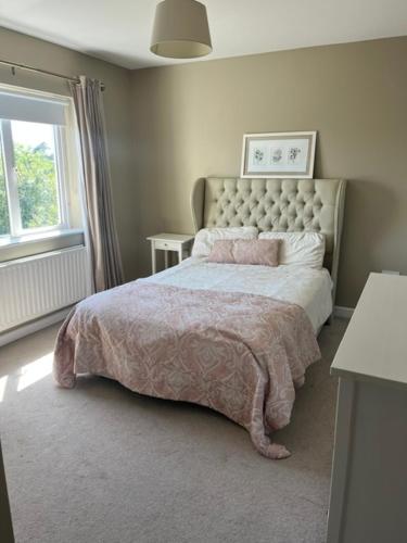 a bedroom with a bed with a pink blanket and a window at Sruthan na Teorainn in Carraroe