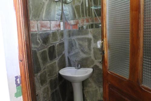 baño con lavabo y pared de piedra en Hostería - Bodega Valle Divino, en Uriondo