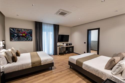 a hotel room with two beds and a television at Corso 84 Luxury Suites in Pescara