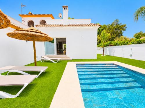 a villa with a swimming pool and a house at Playa Fuente del Gallo I in Conil de la Frontera