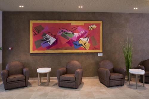 a waiting room with chairs and a painting on the wall at DOMITYS – Le Carroussel in Cabourg