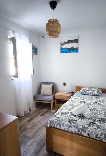 a bedroom with a bed and a chair and a window at Maestral in Nerezine