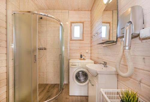 a bathroom with a washing machine and a sink at Domki PoZdrowie in Rusinowo