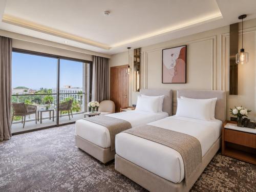 two beds in a hotel room with a balcony at Grand Dominium in Agadir