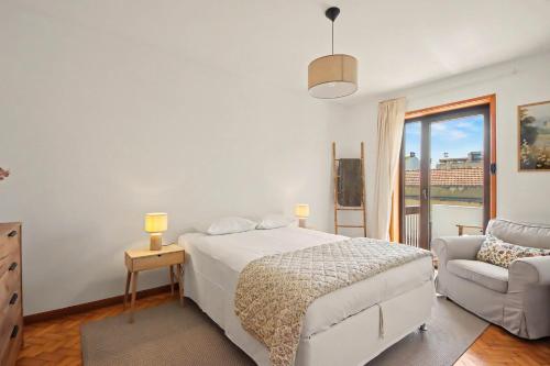 a bedroom with a bed and a chair and a window at Driftwood - Refúgio Perto do Mar in Matosinhos