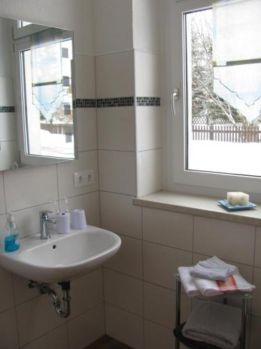 La salle de bains blanche est pourvue d'un lavabo et d'une fenêtre. dans l'établissement Reiterhof & Pension Lienemann, à Grünbach