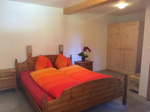 a bedroom with a large wooden bed with orange pillows at BnB Guesthouse Lusi in Frauenkirch