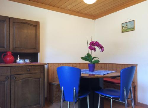 a kitchen with a table and blue chairs at BnB Guesthouse Lusi in Frauenkirch